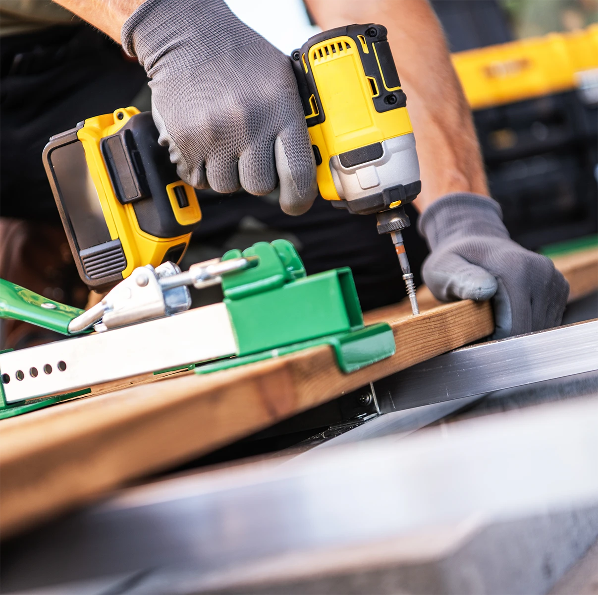 Die Hände eines Dachdeckers arbeiten an einem Dach mit einer Bohrmaschine