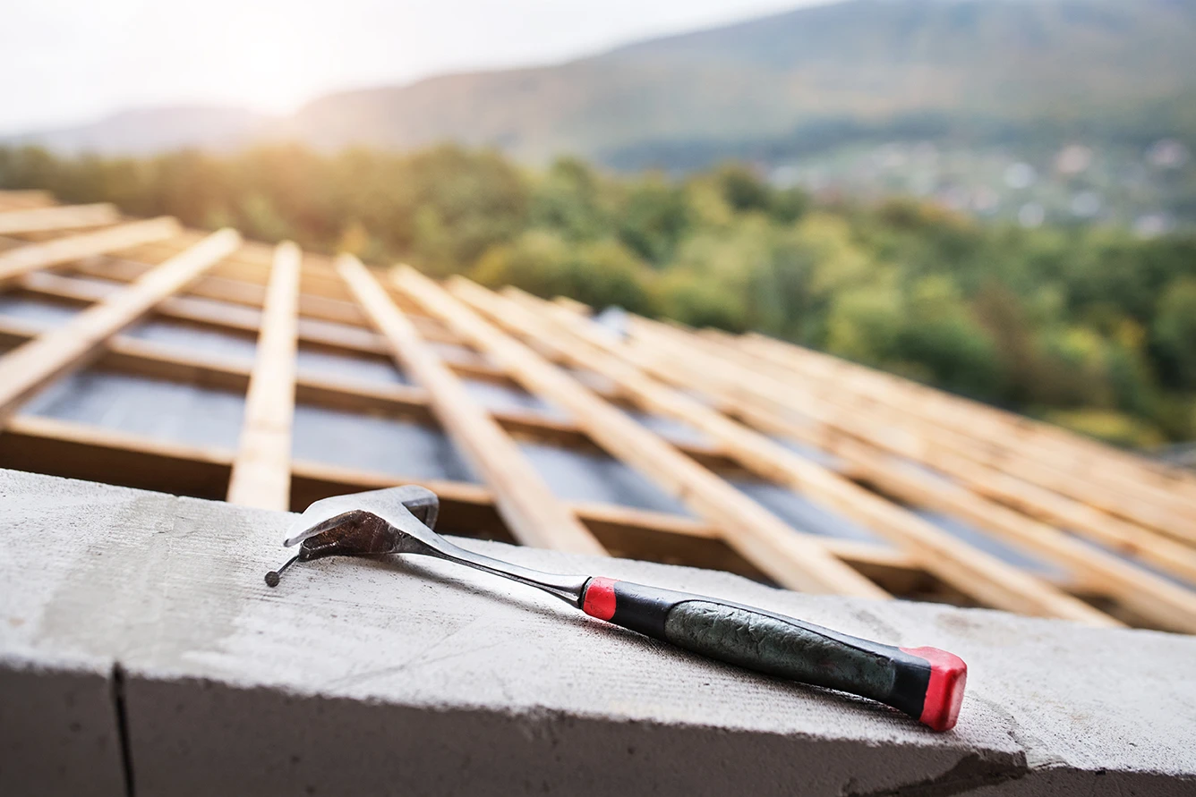 Der Hammer eines Dachdeckers liegt auf einem unfertigen Dach